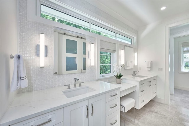 bathroom featuring vanity, backsplash, baseboards, and a wealth of natural light