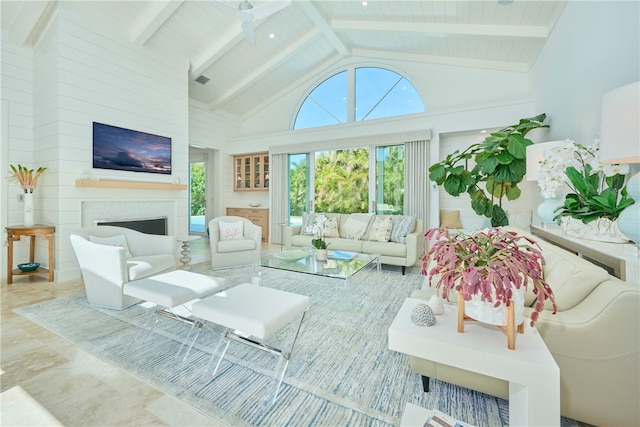 living area featuring beamed ceiling, a fireplace, wooden ceiling, high vaulted ceiling, and a ceiling fan