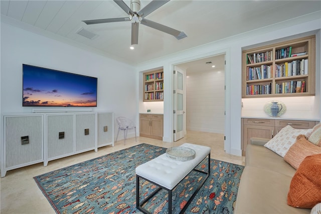 living room featuring built in shelves, ceiling fan, and ornamental molding