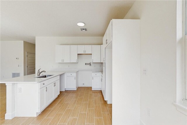 8050 97th Ct, Vero Beach, FL 32967 - kitchen with a sink, a peninsula, white cabinets, and light countertops