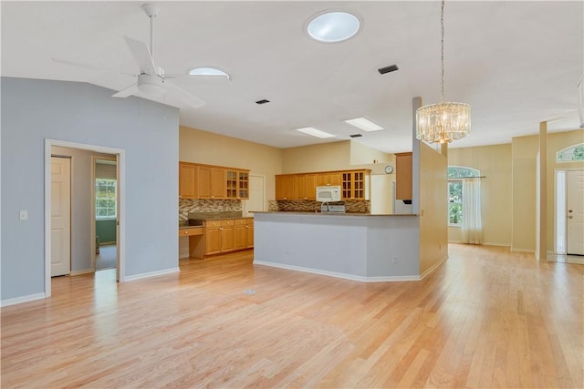 2615 15th St, Vero Beach, FL 32960 - kitchen with white microwave, tasteful backsplash, glass insert cabinets, light wood-style flooring, and ceiling fan