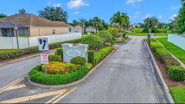 6057 Ridge Lake Cir, Vero Beach, FL 32967 - view of asphalt street featuring curbs, traffic signs, a residential view, and a gated entry