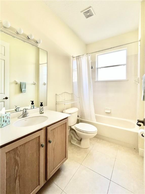 full bathroom featuring toilet, shower / bath combo with shower curtain, vanity, and tile patterned flooring