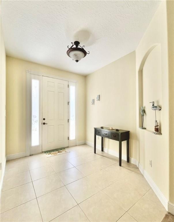 foyer entrance with a textured ceiling and light tile patterned flooring