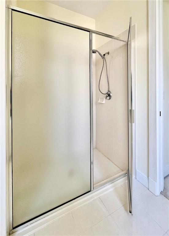 bathroom with a shower with door and tile patterned flooring