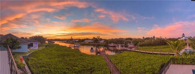 yard at dusk featuring a boat dock and a water view