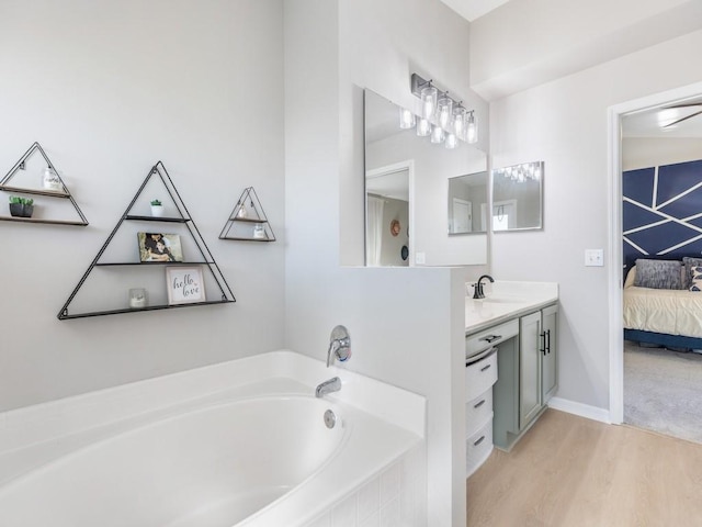 ensuite bathroom featuring vanity, wood finished floors, baseboards, ensuite bathroom, and a bath