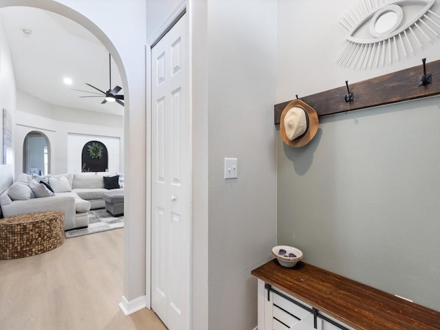 corridor featuring arched walkways and light wood-style floors