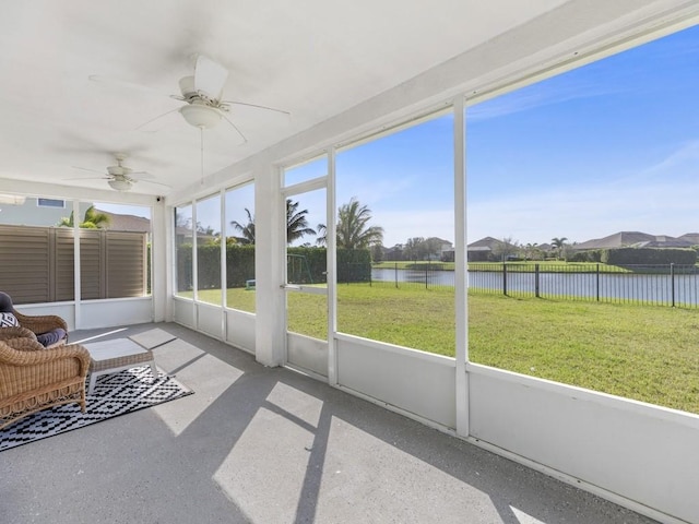 unfurnished sunroom with a ceiling fan, a water view, and a wealth of natural light