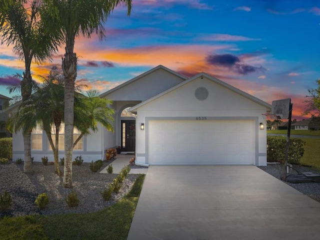 ranch-style house with an attached garage, concrete driveway, and stucco siding