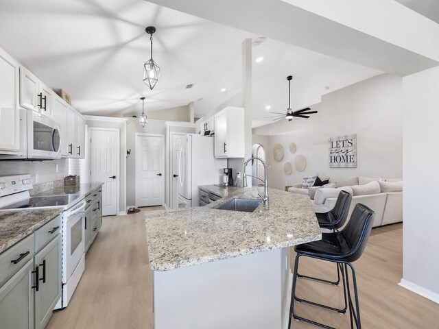 kitchen with light wood-style floors, a sink, white appliances, and vaulted ceiling
