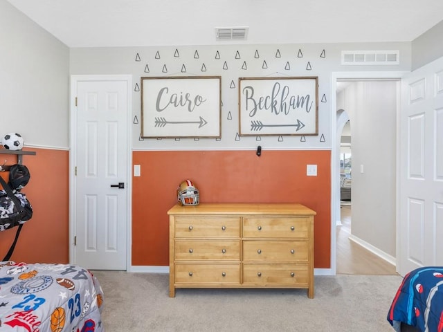 bedroom with arched walkways, visible vents, light colored carpet, and baseboards