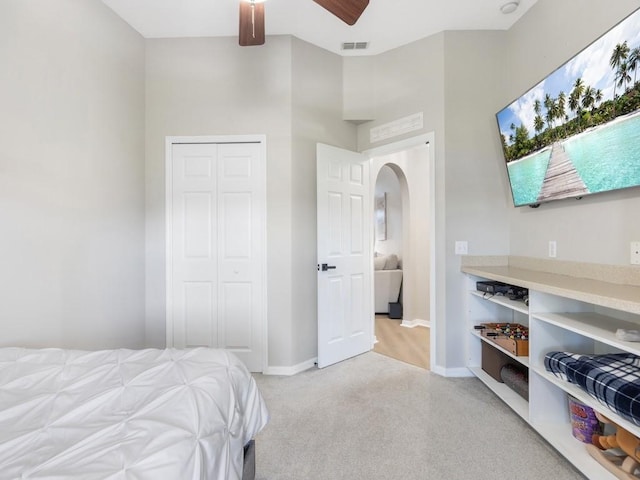 bedroom featuring visible vents, baseboards, light colored carpet, a closet, and arched walkways