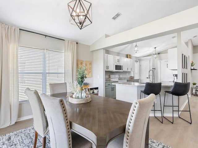 dining space featuring visible vents, lofted ceiling, light wood-style floors, and an inviting chandelier