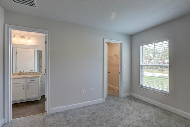 unfurnished bedroom with carpet, visible vents, a spacious closet, and baseboards