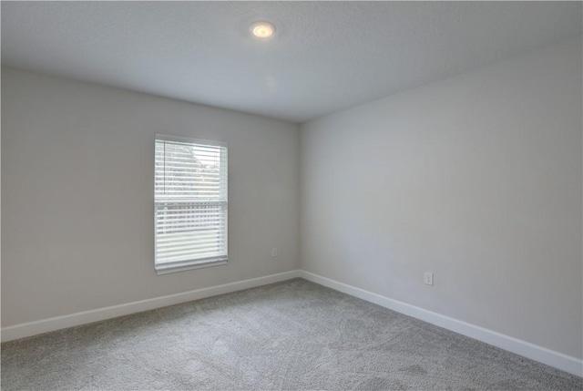 carpeted empty room featuring baseboards