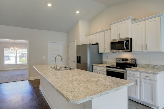 kitchen featuring stainless steel appliances, a kitchen island with sink, vaulted ceiling, a sink, and white cabinetry