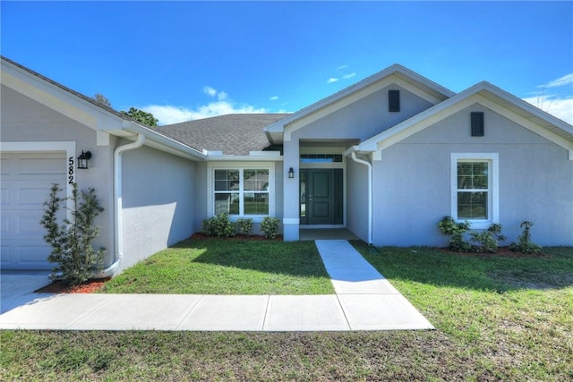 view of front of house featuring a garage, a front yard, a shingled roof, and stucco siding