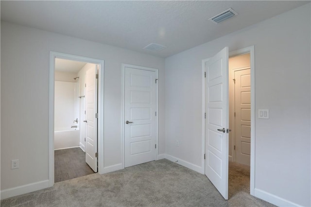 unfurnished bedroom with carpet floors, visible vents, and baseboards