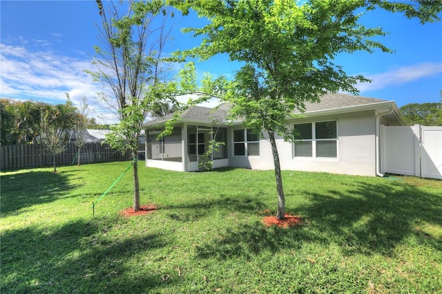 back of house with a yard, a gate, a fenced backyard, and a sunroom