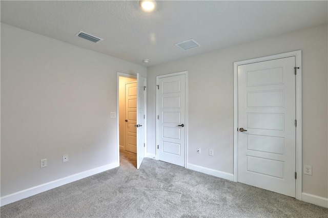 unfurnished bedroom with carpet, visible vents, and baseboards