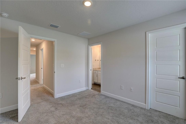 unfurnished bedroom featuring light carpet, visible vents, baseboards, and a textured ceiling