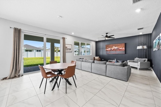 living room featuring ceiling fan and a textured ceiling