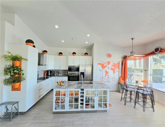 kitchen with white cabinetry, sink, stainless steel fridge, decorative light fixtures, and exhaust hood