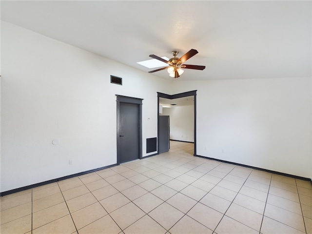 tiled spare room featuring ceiling fan and a skylight