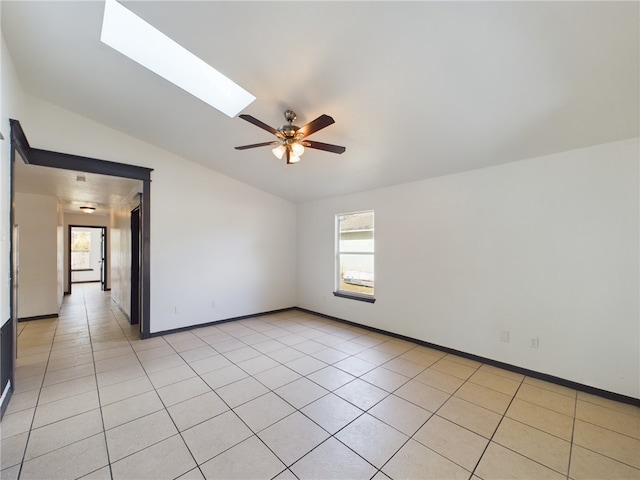 empty room with lofted ceiling with skylight, a healthy amount of sunlight, and light tile patterned floors