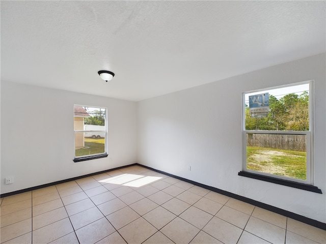 empty room with light tile patterned floors and a textured ceiling