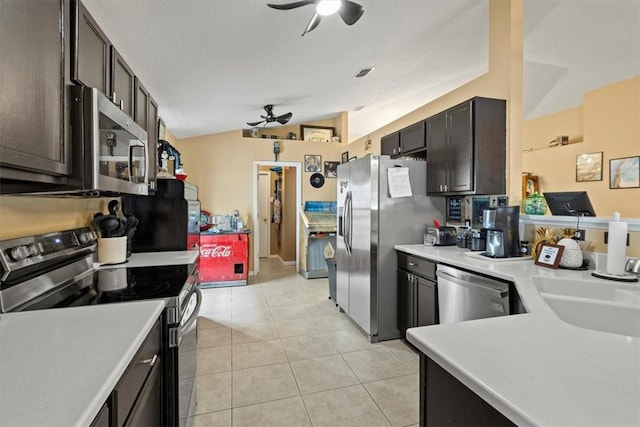 kitchen featuring ceiling fan, stainless steel appliances, vaulted ceiling, and light tile patterned floors