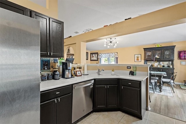 kitchen with sink, a chandelier, light tile patterned floors, appliances with stainless steel finishes, and kitchen peninsula