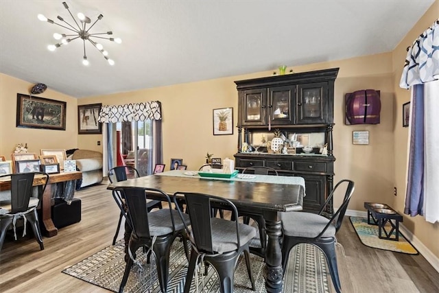 dining area with vaulted ceiling, light wood-type flooring, and a notable chandelier