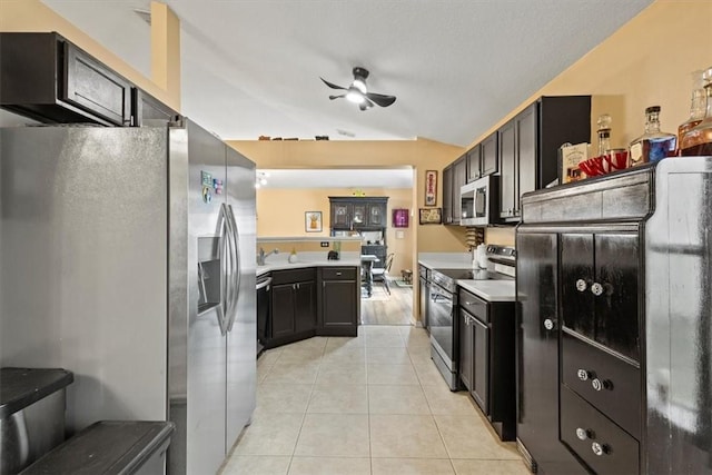 kitchen with lofted ceiling, light tile patterned floors, ceiling fan, appliances with stainless steel finishes, and kitchen peninsula