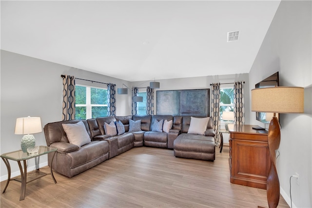 living room featuring a healthy amount of sunlight, light hardwood / wood-style flooring, and lofted ceiling