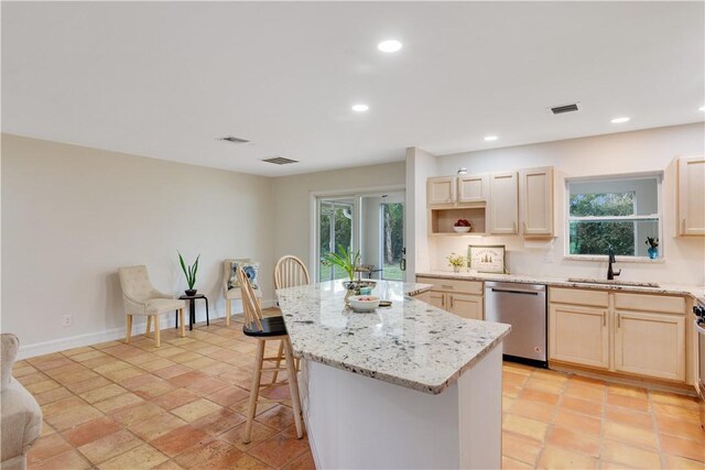 kitchen featuring a kitchen island, a breakfast bar, sink, stainless steel dishwasher, and light stone countertops