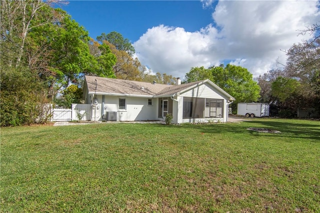 rear view of property with cooling unit, a lawn, and a sunroom