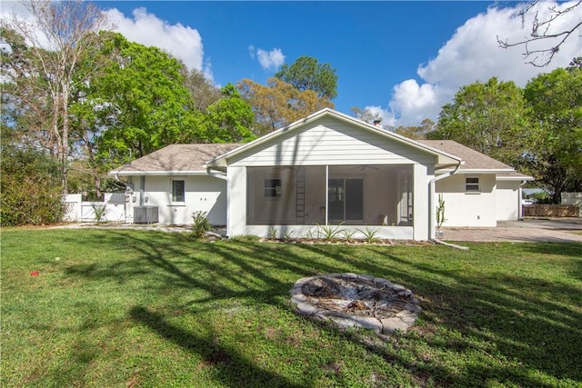 back of house with central AC, a lawn, a sunroom, and an outdoor fire pit