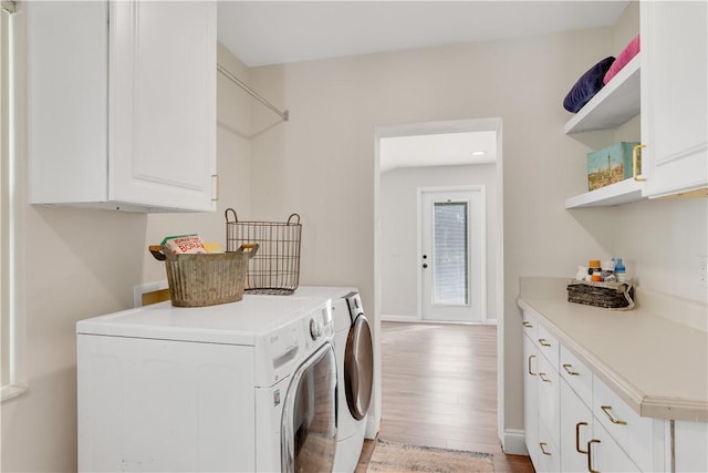 laundry room with cabinets, washing machine and dryer, and light hardwood / wood-style flooring