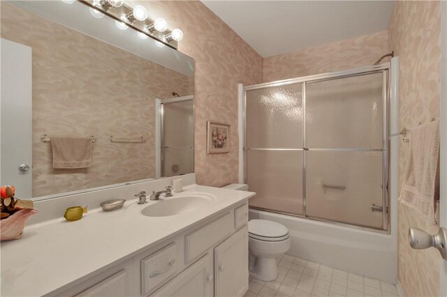 full bathroom with combined bath / shower with glass door, vanity, toilet, and tile patterned flooring