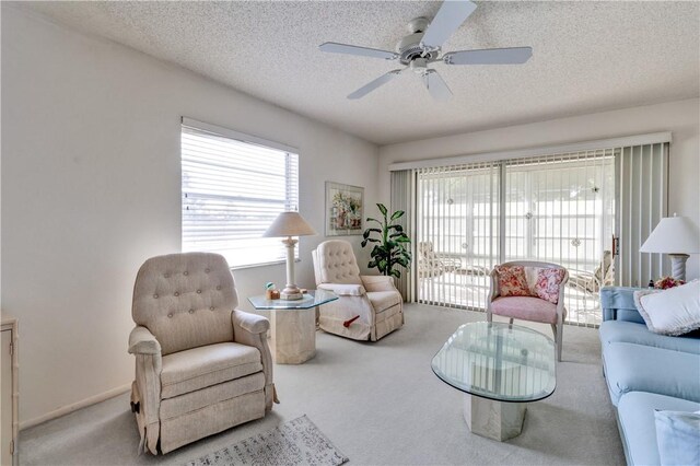 living room featuring ceiling fan, light colored carpet, and a textured ceiling