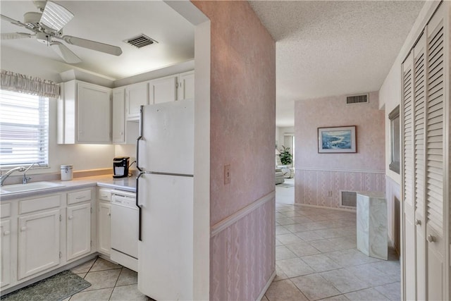 kitchen featuring a textured ceiling, white cabinetry, sink, and white appliances