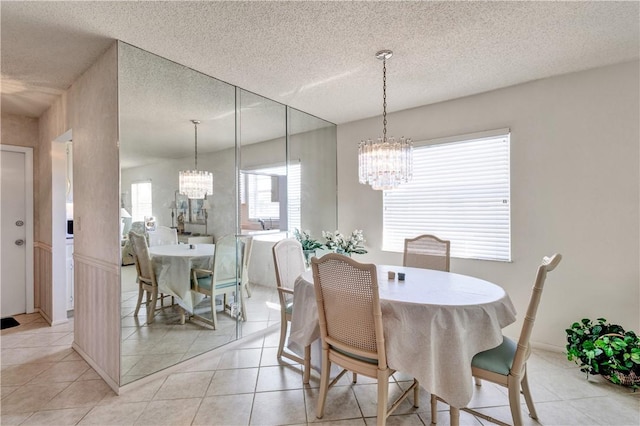 dining space featuring light tile patterned floors, a chandelier, and a textured ceiling