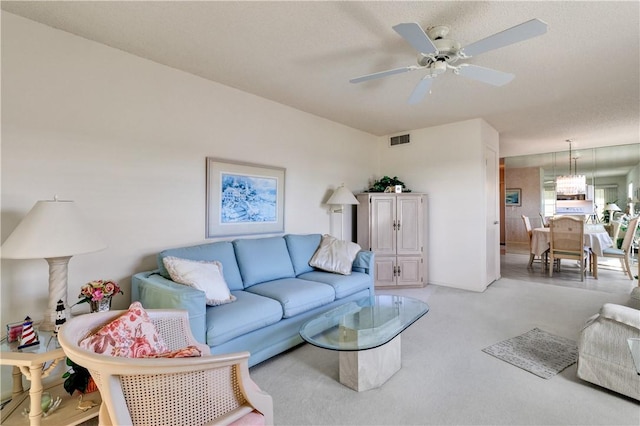 carpeted living room with ceiling fan and a textured ceiling