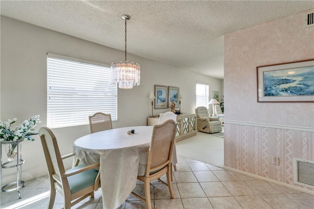 dining room with light tile patterned flooring, a textured ceiling, and an inviting chandelier