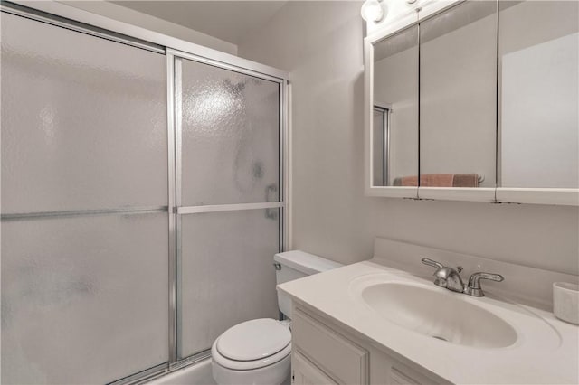 bathroom featuring a shower with door, vanity, and toilet