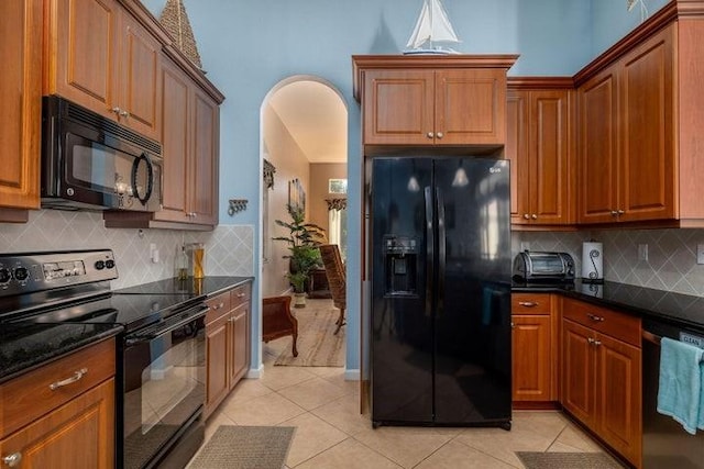 kitchen featuring black appliances, decorative backsplash, light tile patterned floors, and dark stone counters