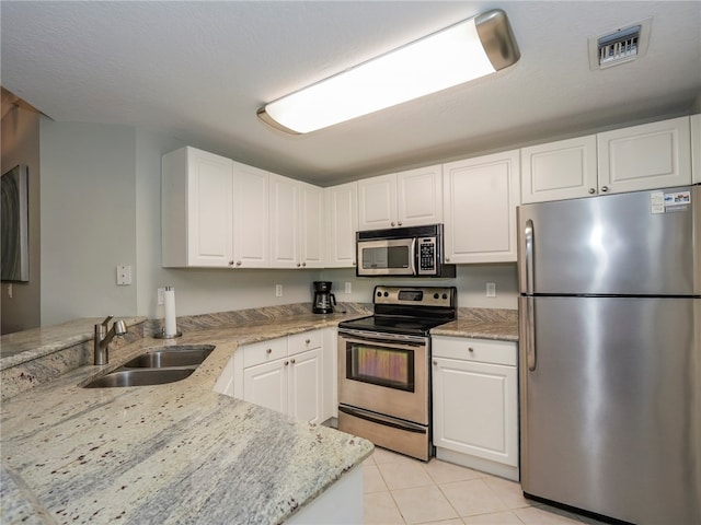 kitchen featuring stainless steel appliances, light stone counters, kitchen peninsula, sink, and white cabinetry