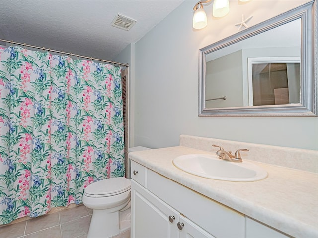 bathroom with toilet, vanity, a textured ceiling, and tile patterned floors